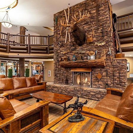 The Grand Hotel At The Grand Canyon Tusayan Εξωτερικό φωτογραφία The photo shows a cozy lodge-style interior with a warm, inviting atmosphere. The focal point is a large stone fireplace with a mounted deer head above it. Surrounding the fireplace are comfortable leather sofas and wooden furniture, creating a rusti