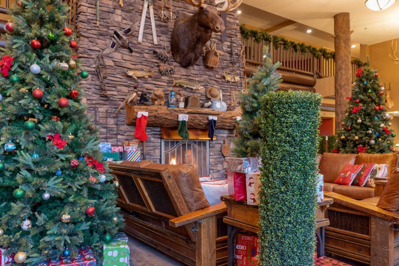 The Grand Hotel At The Grand Canyon Tusayan Εξωτερικό φωτογραφία The photo shows a cozy holiday scene with a rustic aesthetic. In the center, there is a wooden bench in front of a stone fireplace, which is adorned with festive decorations. Above the fireplace, a mounted moose head adds a touch of wilderness charm.
