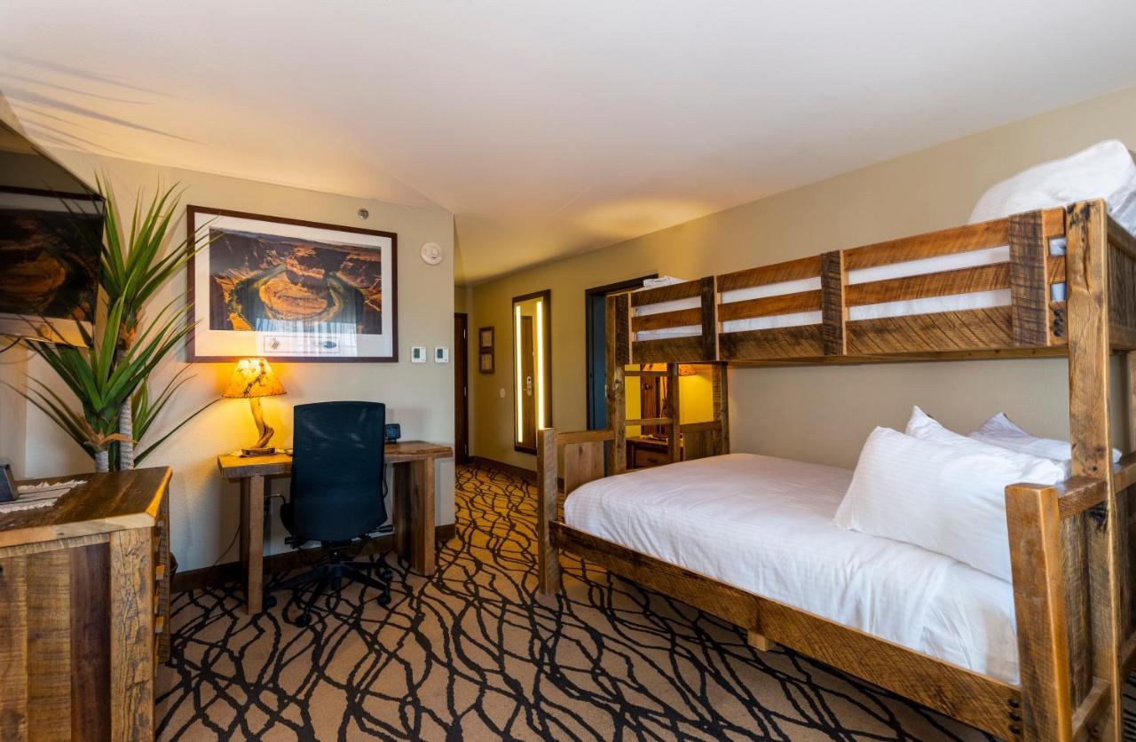 The Grand Hotel At The Grand Canyon Tusayan Εξωτερικό φωτογραφία The photo shows a cozy hotel room. It features a bed with white bedding and a wooden headboard. Beside the bed, there is a bunk bed structure, though it is currently not occupied. A desk with a chair is positioned against one wall, and there is a lar