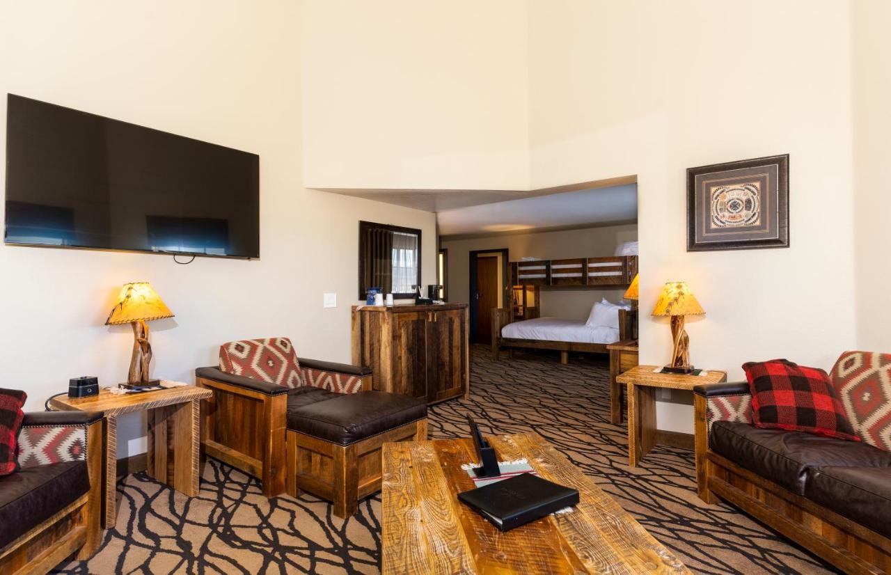 The Grand Hotel At The Grand Canyon Tusayan Εξωτερικό φωτογραφία The photo shows a cozy living area of a hotel or lodge. It features rustic wooden furniture, including armchairs and a coffee table. A large flat-screen TV is mounted on the wall. There are lamps with warm lighting and decorative patterns on the furn