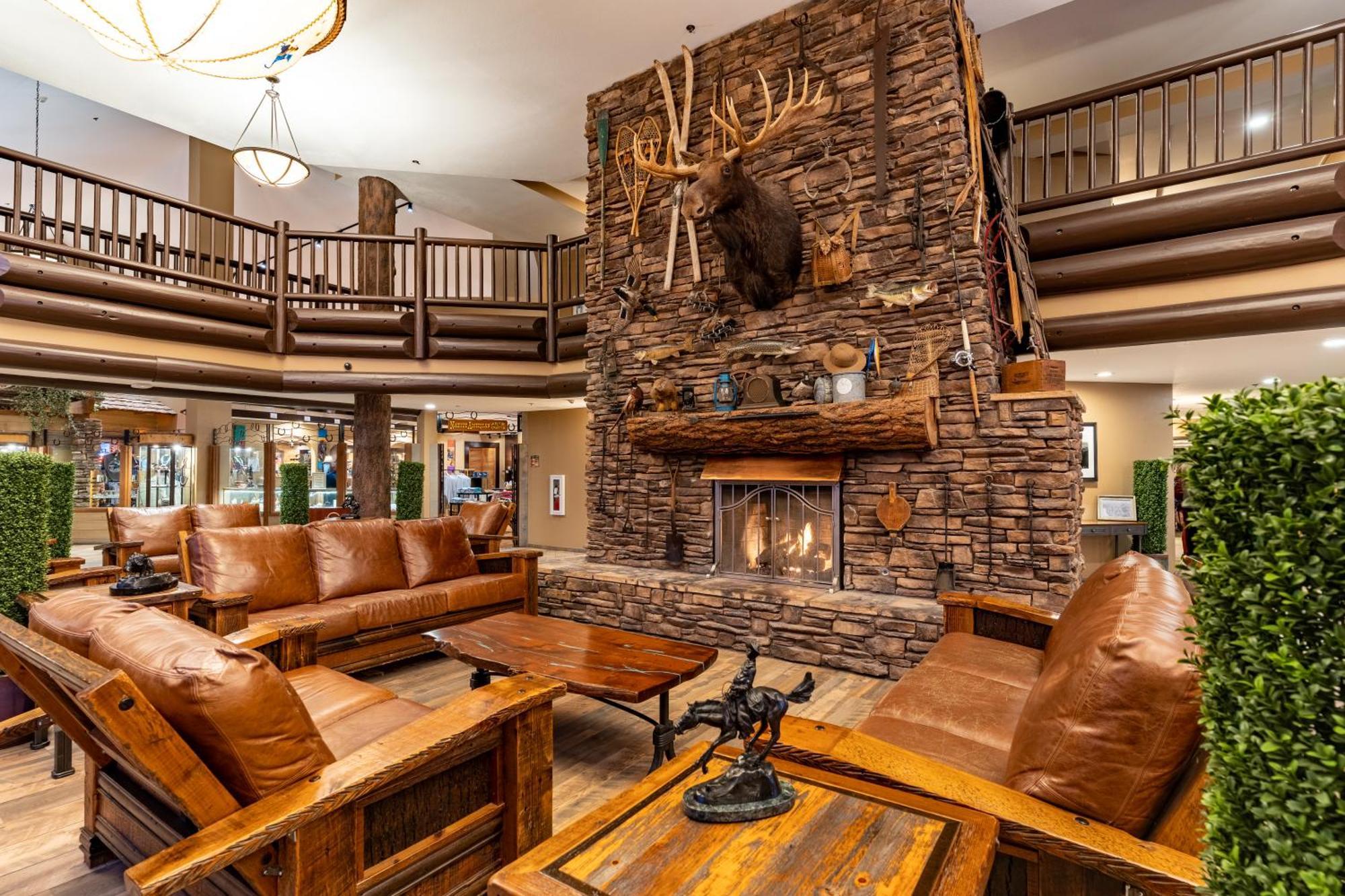 The Grand Hotel At The Grand Canyon Tusayan Εξωτερικό φωτογραφία The photo shows a cozy lodge-style interior with a warm, inviting atmosphere. The focal point is a large stone fireplace with a mounted deer head above it. Surrounding the fireplace are comfortable leather sofas and wooden furniture, creating a rusti